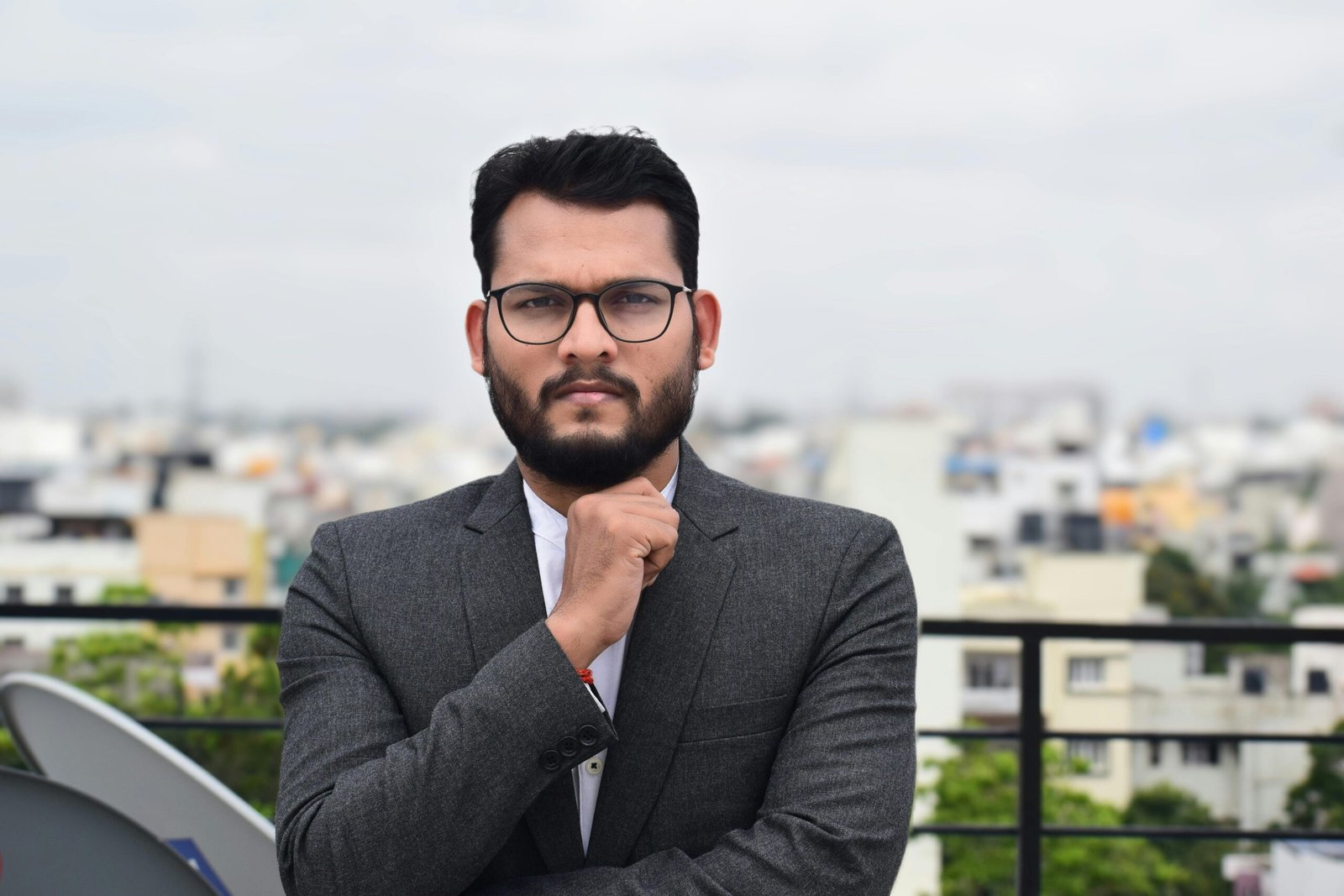 Confident man in business attire standing on an urban rooftop during the day.